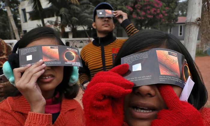  Trẻ em tại Kolkata, Ấn Độ dùng tấm kính để quan sát hiện tượng này. Ảnh: Reuters. 