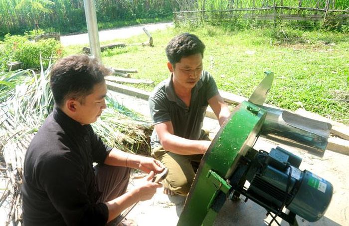 Trưởng thôn Cháng A Bào (bên trái), thôn Tiên Tốc, xã Bình An (Lâm bình) luôn gần gũi, sâu sát với người dân. Trong ảnh: Anh Bào giúp đỡ người dân trong thôn sửa chữa máy thái cỏ cho gia súc.Ảnh: Thủy Châu