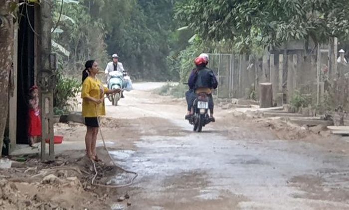 Hằng ngày người dân phải tưới nước chống bụi đoạn đường trước cổng trạm trộn.