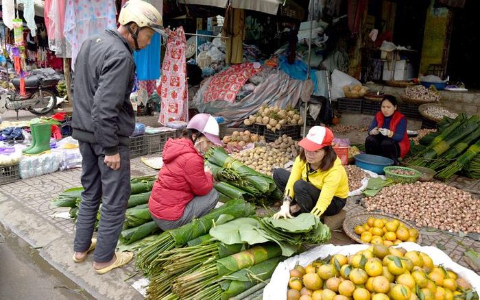 Người dân đi chợ mua lá dong về gói bánh chưng.