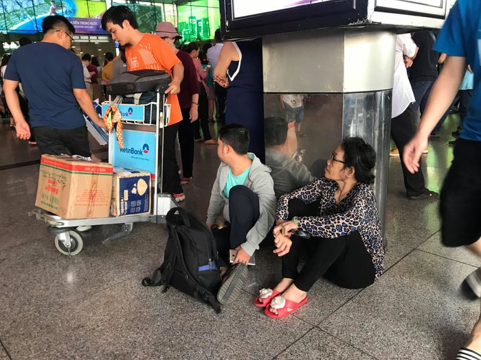 Số lượng hành khách quá đông, các dãy ghế đợi không đủ khiến người dân phải ngồi vật vờ dưới nền nhà ga.