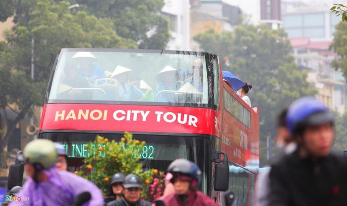 Du khách nước ngoài thích thú đội nón ngắm thành phố dưới mưa xuân. Đây có lẽ là một trải nghiệm độc đáo cho những vị khách đến với Hà Nội vào đúng dịp Tết Nguyên đán. 