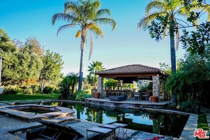Không gian thư giãn ngoài trời bao gồm quầy bar, hồ bơi, bồn tắm nước nóng, và sân vườn được chăm chút tỉ mỉ.