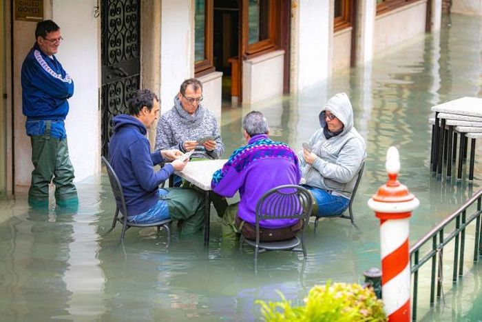 Người dân địa phương ngồi chơi bài trên đường phố ngập nước ở Venezia, Ý, ngày 17/11/2019. (Ảnh: IPA)