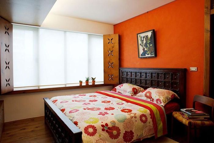 Chiếc giường gỗ chạm khắc tỉ mỉ cùng bức tường đầu giường sơn cam giúp người sử dụng luôn cảm thấy ấm áp và dễ chịu, dễ dàng có được giấc ngủ sâu, thoải mái.