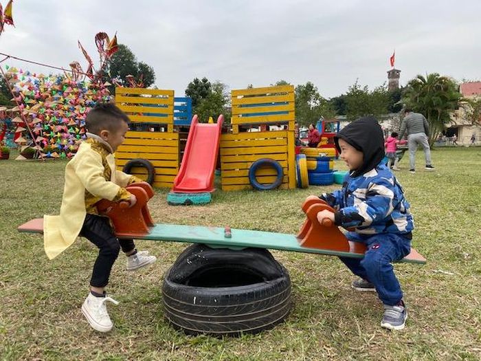  Các em nhỏ trải nghiệm trò chơi bập bênh tại khu vui chơi ngoài trời.