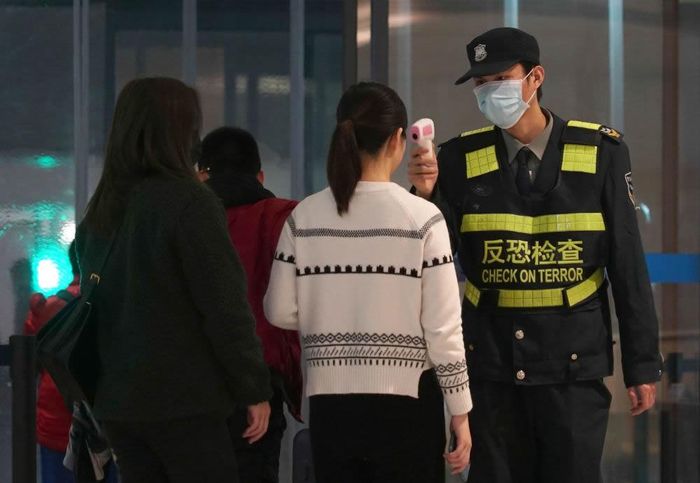 Nhân viên sân bay Vũ Hán đo nhiệt độ kiểm tra thân nhiệt hành khách. Ảnh: Reuters