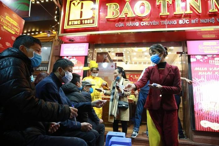 Nhân viên cửa hàng Bảo Tín Minh Châu phát khẩu trang, số thứ tự cho khách hàng.