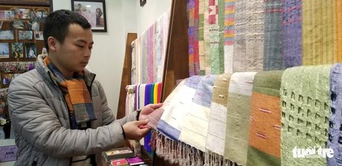Chàng trai trẻ Phan Bá Tân giới thiệu dòng khăn quàng từ tơ tằm - Ảnh: HÀ THANH