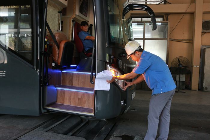 Cán bộ Trung tâm Đăng kiểm xe cơ giới Nghệ An kiểm tra hệ thống đèn chiếu sáng, hạn chế tình trạng "độ" thêm đèn đối với xe khách. Ảnh tư liệu
