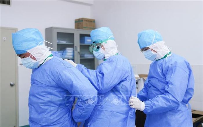 Các nhân viên y tế giúp đỡ nhau mặc quần áo bảo hộ tại khu vực cách ly điều trị cho bệnh nhân nhiễm virus corona của bệnh viện ở Chương Châu, tỉnh Phúc Kiến, Trung Quốc. Ảnh: THX/TTXVN