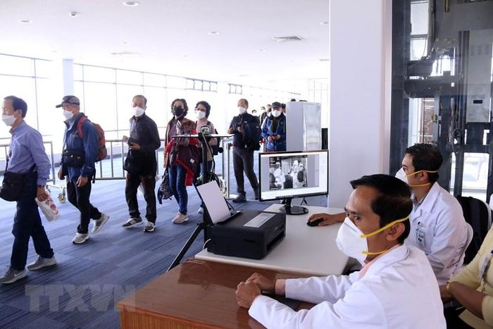 Hành khách đến Lào qua các cửa khẩu quốc tế sẽ được kiểm tra thân nhiệt, sau đó sẽ được yêu cầu sát khuẩn tay trước khi nhập cảnh Lào. (Ảnh: Phạm Kiên/Vietnam+)