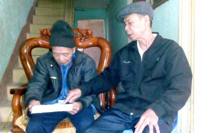 Cựu Chiến binh Hoàng Đức Quân (bên phải), 97 tuổi, ở khu 5, xã Yên Kiện, huyện Đoan Hùng lật giở những trang tài liệu ghi lại quá trình hoạt động cách mạng của mình.