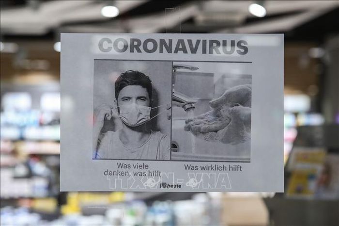 Tấm biển kêu gọi người dân rửa tay thường xuyên và đeo khẩu trang để phòng tránh lây nhiễm COVID-19 tại một hiệu thuốc ở Berlin, Đức, ngày 3/3/2020. Ảnh: THX/TTXVN