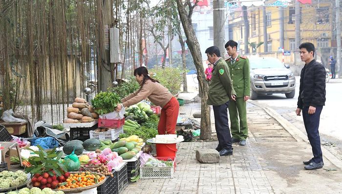 Lực lượng chức năng nhắc nhở các hộ bán hàng tại khu 11, thị trấn Thanh Ba không lấn chiếm hành lang ATGT.