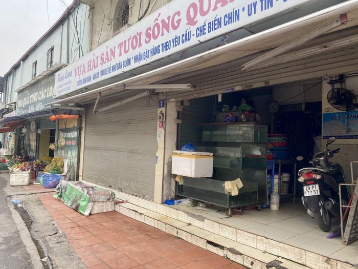 Bên ngoài chợ Kim Liên, một cửa hàng lớn chuyên kinh doanh hải sản cũng đóng cửa. Vắng khách, chị Hòa - bán gà tại chợ Kim Liên còn tranh thủ bật TV nhỏ tại quầy để tập thể dục.
