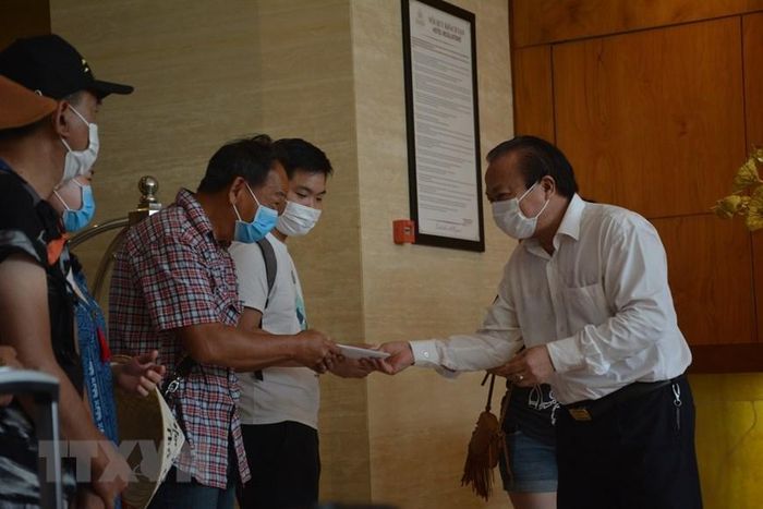 Chủ tịch UBND quận Hải Châu Lê Anh phát giấy chứng nhận hoàn thành cách ly y tế cho các khách cách ly tại khách sạn. (Ảnh: Văn Dũng/TTXVN)