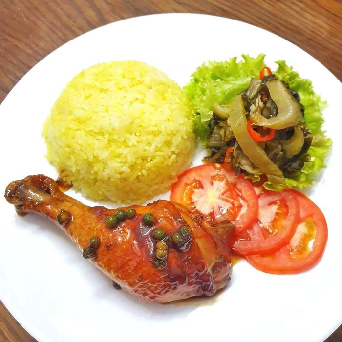 Điểm nhấn của món chính là sự hòa quyện đậm đà giữa cơm, gà, cà chua và rau ăn kèm. Cơm ở đây được thực khách đánh giá mềm, mịn, gà ướp vừa ăn và béo ngậy. Bạn có thể chọn phần cơm lớn hoặc nhỏ tùy sức ăn với mức giá dao động từ 33.000-52.000 đồng. Ảnh: Amthucdelichi.