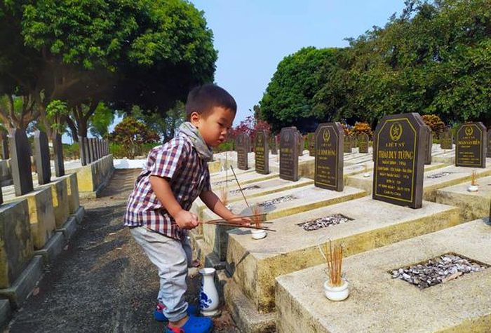 Đưa con đến nghĩa trang liệt sĩ thắp hương là một cách giáo dục truyền thống. Ảnh: T.N.Đ