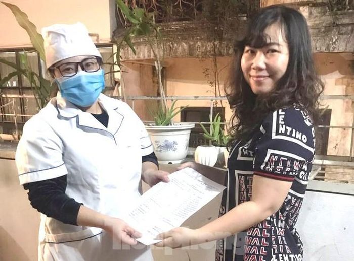 Chị Hà nhận quyết định hết cách ly từ cán bộ y tế của phường.