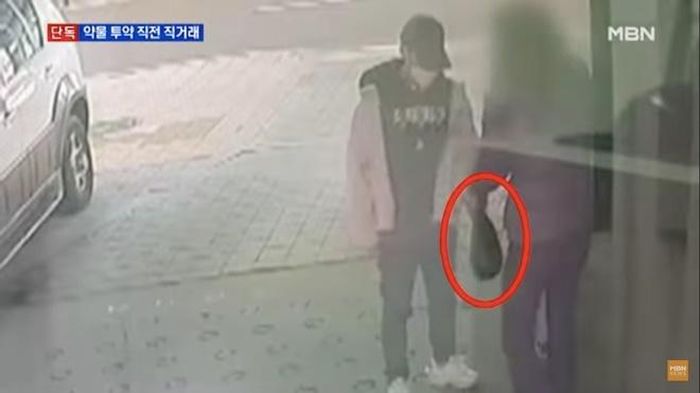 Nam thần tượng nhận túi đồ màu đen từ người đàn ông lạ mặt.