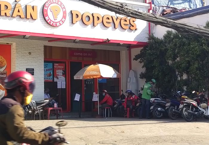Trong khi đó, cũng như nhiều hàng quán tuân thủ chặt chẽ việc bán hàng mang đi (take away), một cửa hàng kinh doanh thức ăn nhanh đã bố trí bàn đón khách trước cửa bước vào tiệm để hạn chế nguy cơ truyền nhiễm bệnh tật. Trên bàn có đặt chai xịt kháng khuẩn để khách hàng và tài xế xe công nghệ sử dụng khi đến mua hàng