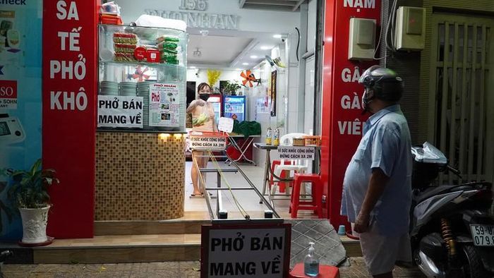 Ông Đỗ Hải Sơn đứng đợi bên ngoài để lấy phở với khoảng cách an toàn là 2 m. Ảnh: NGUYỄN TIẾN