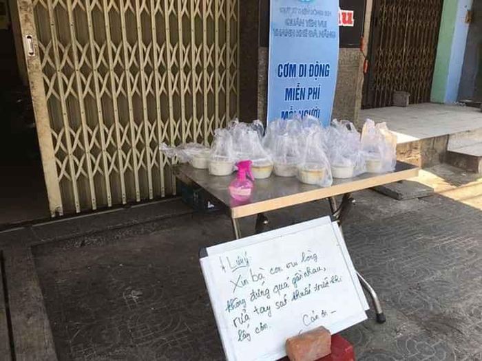 Những điểm phát cơm cố định, anh Nguyễn Duy Đức cùng với mọi người đặt sẵn những suất ăn trưa trên bàn để người nghèo ai cần thì đến lấy kèm với một lưu ý: “Xin bà con vui lòng không đứng quá gần nhau, rửa tay sát khuẩn trước khi lấy cơm. Cảm ơn”