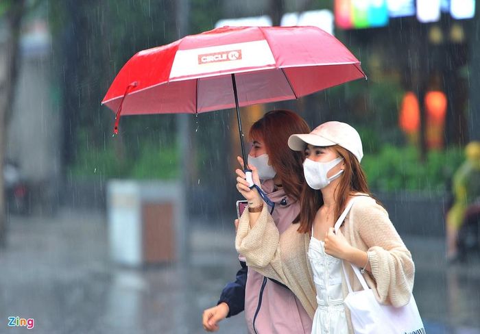 2 bạn trẻ trên phố đi bộ Nguyễn Huệ khá thích thú với cơn mưa nhẹ đầu mùa. Cả hai dùng ô tránh mưa đi dạo, thỉnh thoảng chụp ảnh cùng nhau.