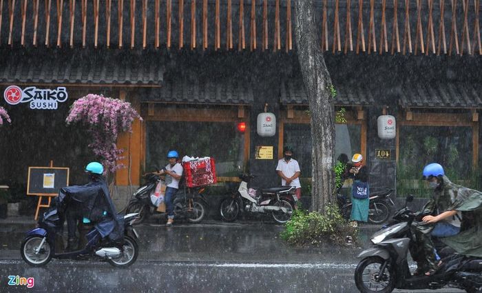 Cơn mưa bất ngờ khiến nhiều người không kịp trang bị áo mưa. Họ tạt vào vỉa hè, nơi có các mái che để trú.