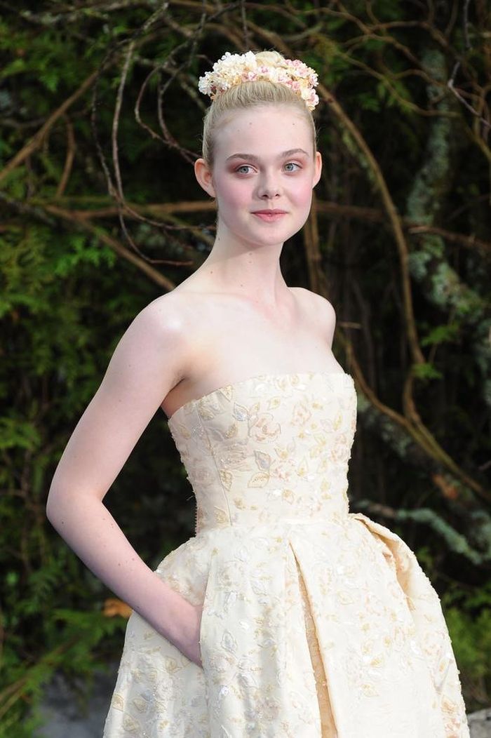 Làn da trắng mịn màng của Elle Fanning phù hợp với mọi loại trang phục khoác trên người. Mẫu váy cúp ngực đính kết những cánh hoa 3D cùng gam màu hồng, vàng pastel càng làm tôn lên vẻ quý phái của tiểu thư yêu kiều. 