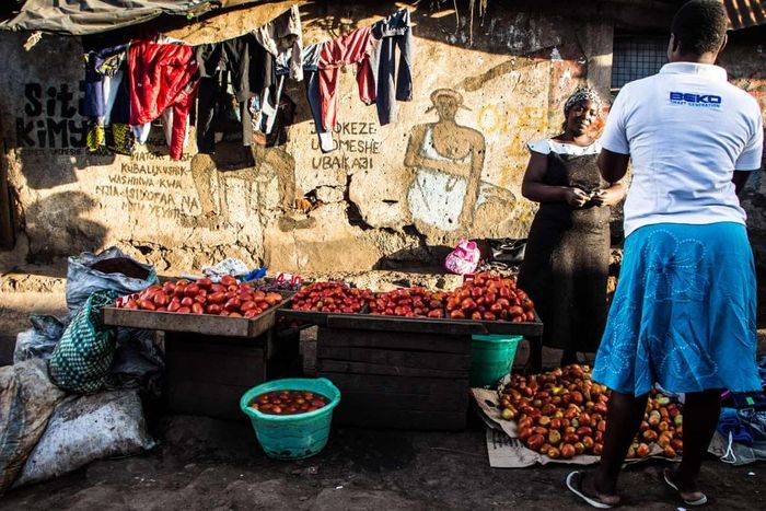 Quầy hàng bán cà chua trước một bức tường lụp xụp ở Kibera. Ảnh: Kelvin Juma.
