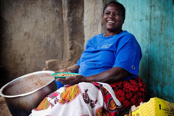Mary Nasia nấu và bán đậu để kiếm sống bên đường ở Kibera. Cô chia sẻ: "Người ta thích đậu của tôi và tôi rất vui khi ngồi đây và nhìn thế giới trôi qua". Ảnh: Kate Holt.