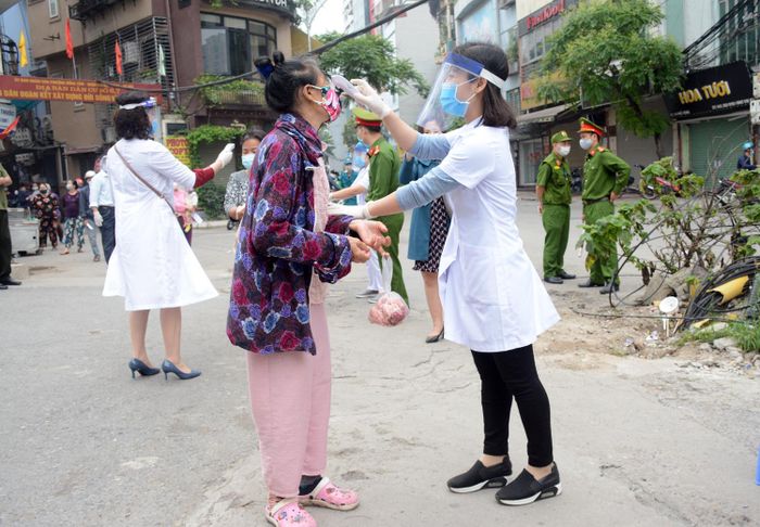 Người dân được kiểm tra thân nhiệt trước khi vào nhận gạo.