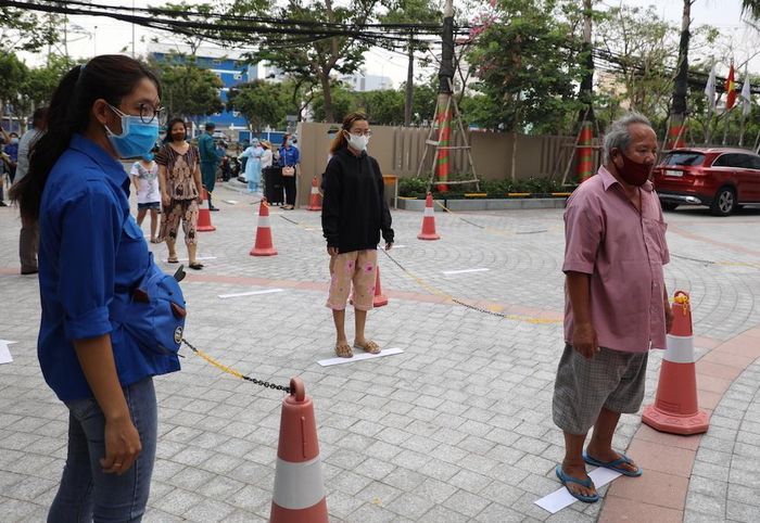 Đội ngũ đoàn thanh niên hỗ trợ hướng dẫn mọi người đứng cách nhau 2m