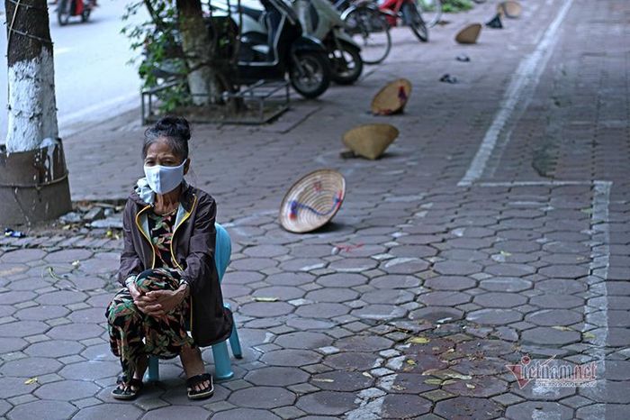 Không cần dùng đồ vật thế chỗ, cụ bà này mang theo chiếc ghế nhựa ngồi đợi đến lượt nhận hỗ trợ.