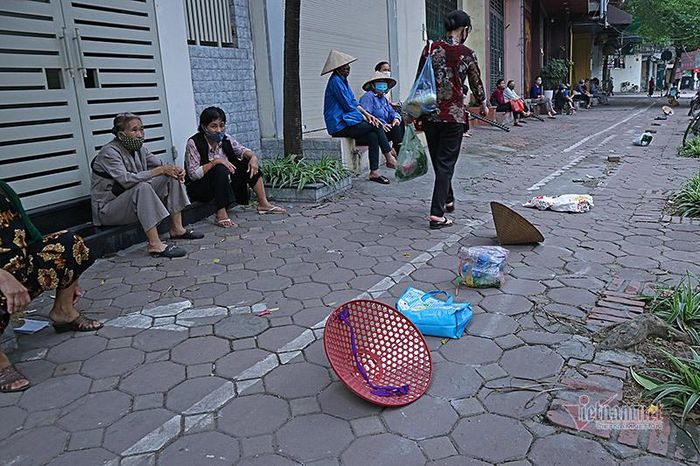 Để đỡ phải đứng lâu gây mỏi mệt, người dân dùng đồ vật mang theo đặt vào giữa những vòng tròn cách nhau 2m đã được kẻ sẵn, còn người thì ngồi bên đợi đến lượt nhận lương thực, thực phẩm.