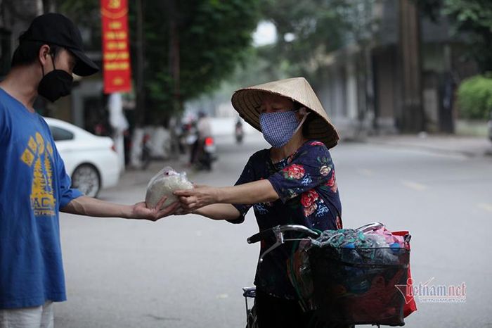 Đã quen thuộc nên khi bà Vũ Thị Trà, quê ở Phù Cừ, Hưng Yên vừa rà chiếc xe đạp đến vỉa hè, một tình nguyện viên đã mang phần quà đưa tận tay bà Trà. Bà Trà, 60 tuổi đã nhiều năm nay làm công việc dọn nhà theo giờ ở Hà Nội, từ khi thực hiện giãn cách xã hội, bà nghỉ ở nhà trọ nên từ lúc đó bà sống nhờ vào tấm lòng của những người hảo tâm.