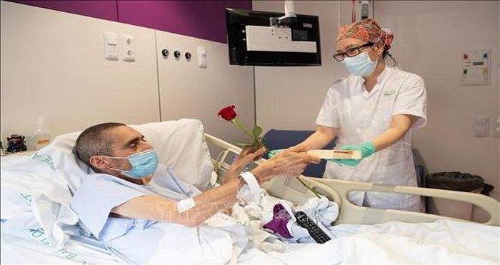Nhân viên y tế tặng hoa và sách cho bệnh nhân nhiễm COVID-19 tại bệnh viện ở Barcelona, Tây Ban Nha, ngày 23/4/2020. Ảnh: THX/TTXVN