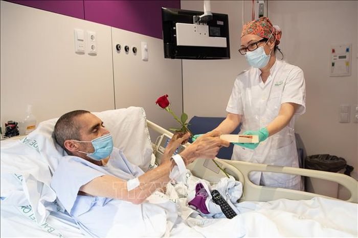Nhân viên y tế tặng hoa và sách cho bệnh nhân nhiễm COVID-19 tại bệnh viện ở Barcelona, Tây Ban Nha, ngày 23/4/2020. Ảnh: THX/TTXVN