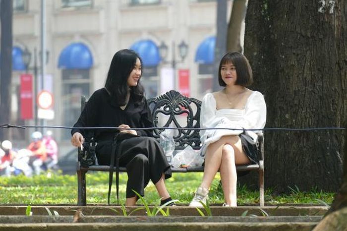 Đôi bạn trẻ ngồi trò chuyện vui vẻ dưới những gốc chò cổ thụ