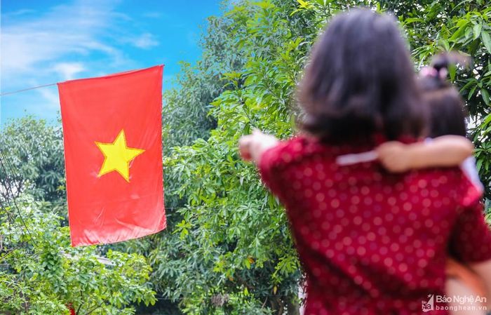 Dịp này, các bậc phụ huynh thường giáo dục con, cháu về ý nghĩa của lá cờ Tổ quốc và những dấu son lịch sử chói lọi của dân tộc. Trong ảnh: Chị Nguyễn Thị Thu Hương, khối An Vinh, phường Hưng Phúc dạy con gái nhỏ về ý nghĩa của lá cờ Tổ quốc. Ảnh: Đức Anh