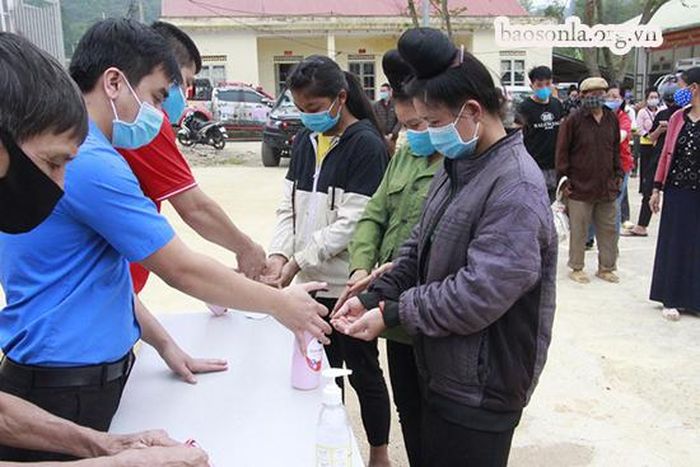 Người dân sát khuẩn tay trước khi vào nhận gạo