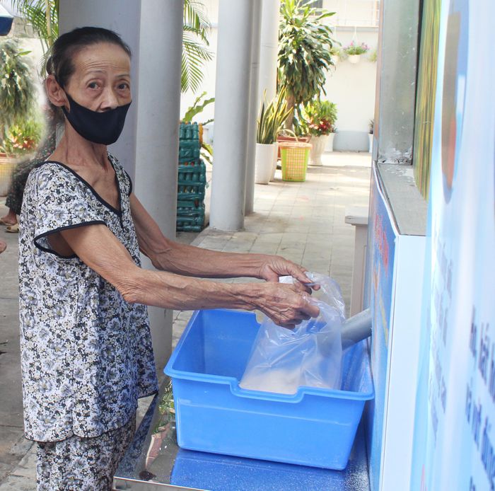 Người dân nghèo nhận gạo tại máy "ATM gạo" của Hội Cựu chiến binh quận Phú Nhuận, TP Hồ Chí Minh phối hợp với các đoàn thể.