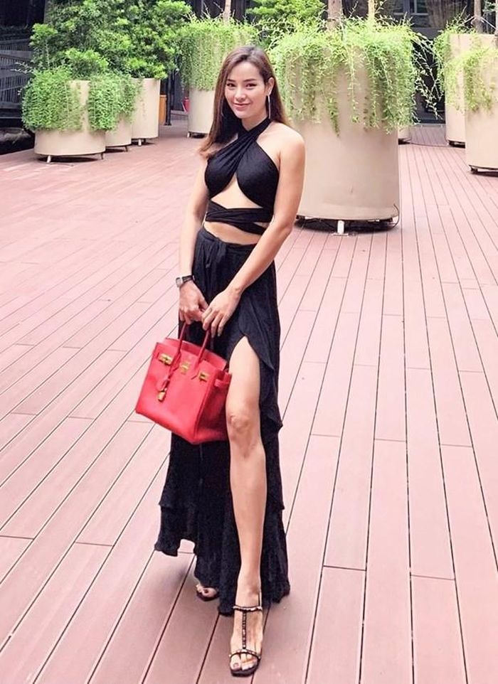 Sau phiên bản màu trắng, Phương Trinh Jolie tiếp tục diện bộ đồ cắt xẻ ''hiểm hóc'' tuyền đen, nhấn nhá bằng túi Hermès đỏ rực. Thêm đôi sandals cao gót, cô nàng đã có phép cộng lý tưởng, chẳng những làm bật lợi thế chân dài mà còn khoe được 3 vòng quyến rũ.
