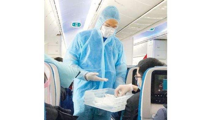 Tiếp viên Vietnam Airlines mời hành khách chuyến bay VN001 nhận khẩu trang