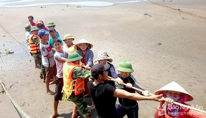 Lực lượng của Đồn Biên phòng Diễn Thành cùng ngư dân tập trung kéo tàu lên trong sáng 16/5. Ảnh: Q.A