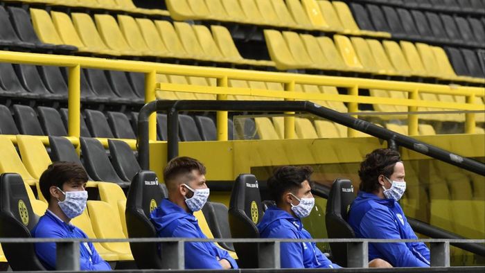 Các cầu thủ dự bị ngồi cách nhau 1,5m trên khán đài không có khán giả trong ngày Bundesliga trở lại thi đấu