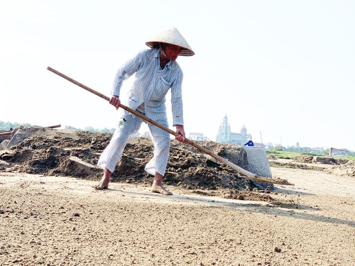 Cụ Đặng Văn Phát dầm chân trần dưới ruộng để cào đất dưới nắng hè gay gắt 