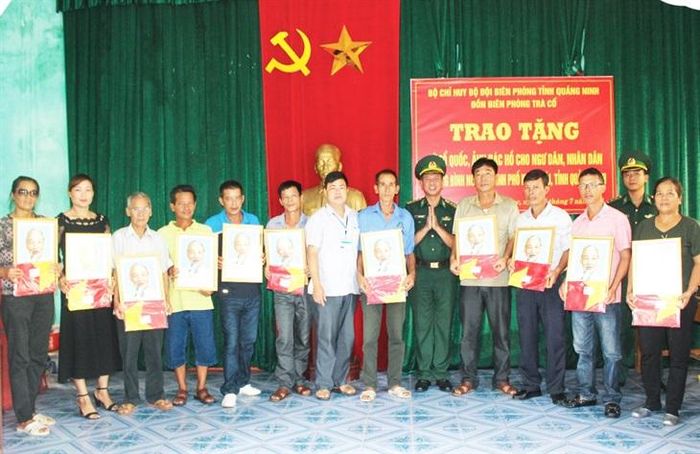 Cán bộ Đồn Biên phòng Trà Cổ tặng cờ Tổ quốc và ảnh Bác Hồ cho ngư dân trên địa bàn. Ảnh: Viết Hà